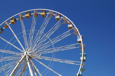 Low angle view of ferris wheel against blue sky