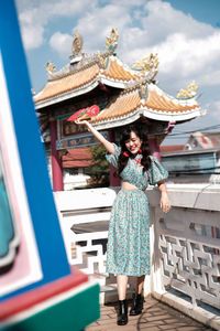 Portrait of woman in blue modern cheongsam holding a red fan at chinese temple 