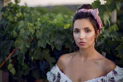 Portrait brunette woman in a white dress stands in a vineyard in summer in italy