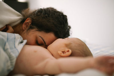 Close-up of mother playing with cute daughter lying on bed at home