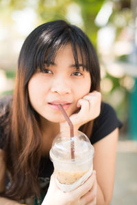 Close-up portrait of young woman drinking coffee in disposable cup