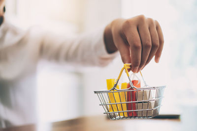 Cropped image of woman hand holding shopping basket with shopping bags