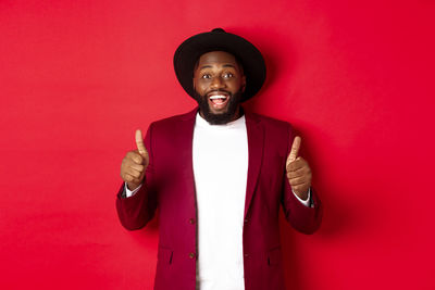 Portrait of man standing against red wall