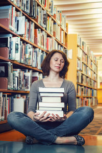Portrait of young woman sitting on book