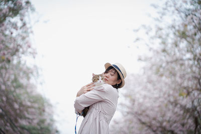 Asian woman travel outdoor with her cat with pink flower in springtime season