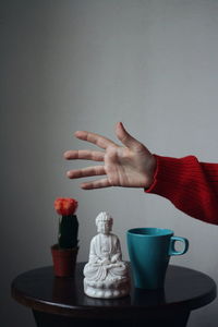 Close-up of hand holding coffee cup on table