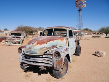 Abandoned car on land against clear blue sky