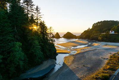 Scenic view of mountains at beach against clear sky during sunset