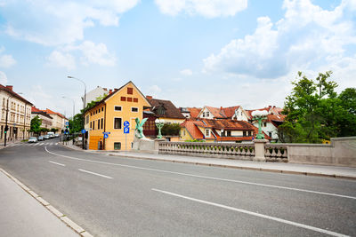 Road by buildings against sky in city