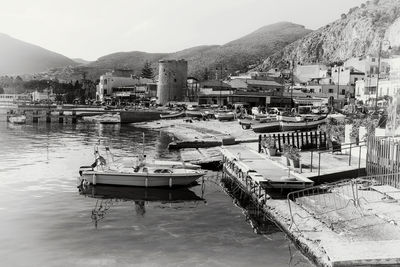 Boats moored at harbor by buildings against sky