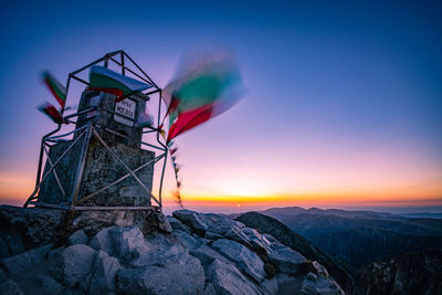 Traditional windmill on mountain against sky during sunset