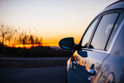 Close-up of car on road against sky during sunset