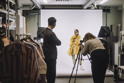 Female fashion model posing against backdrop during photo shoot at studio