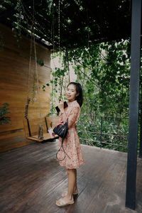 Full length of woman standing against tree