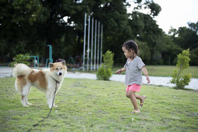 Side view of woman with dog running on field