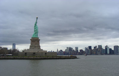 Statue of liberty and sea against cloudy sky