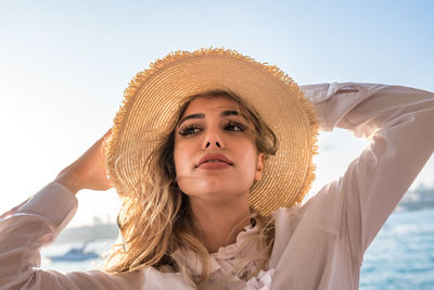 Portrait of beautiful young woman against sky