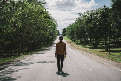 Man standing on road amidst trees