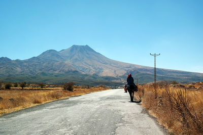Rear view of man riding motorcycle on road against sky
