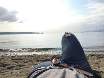 Low section of man on beach against sky