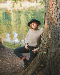 Portrait of teenage girl standing by tree trunk