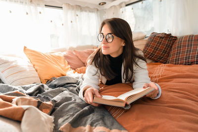 Young woman using mobile phone while lying on bed at home