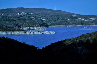 Scenic view of lake and mountains against clear blue sky