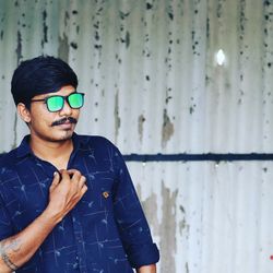 Portrait of young man standing against wall