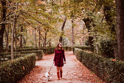 Smiling woman walking with dog on footpath