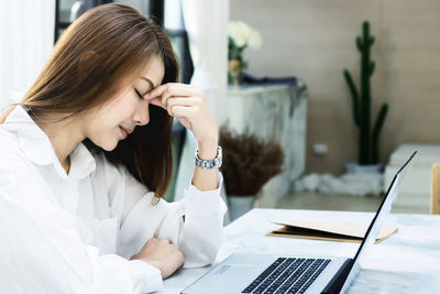 Woman using phone while sitting on table