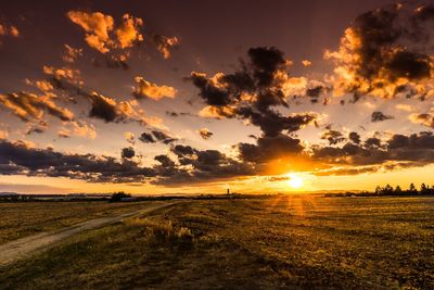 Scenic view of landscape against dramatic sky during sunset