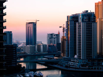 River amidst buildings against sky at dusk in city