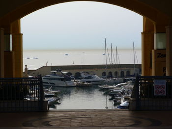 Sailboats moored at harbor against clear sky