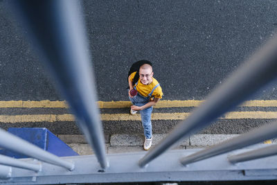 Smiling non-binary person with backpack seen through railings on street