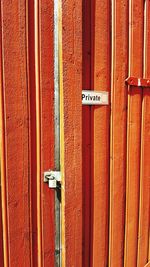 Private text on closed orange door during sunny day