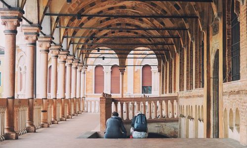 Rear view of people sitting in corridor of historical building