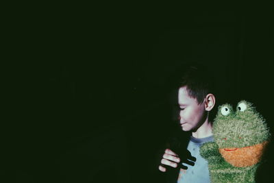 Boy with puppet against black background