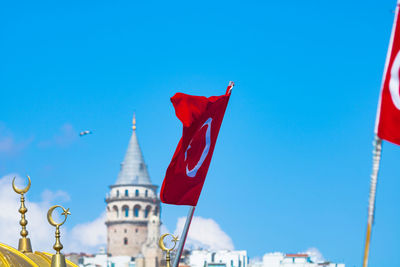 Low angle view of flags against buildings against blue sky
