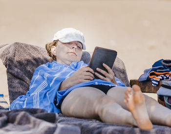 Full length of woman using digital tablet while sitting on lounge chair