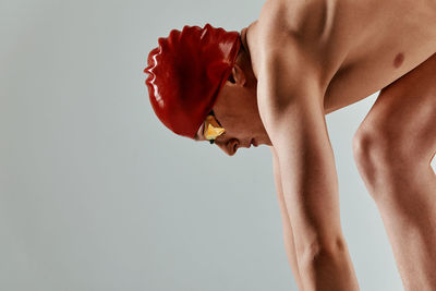 Side view of shirtless man standing against white background