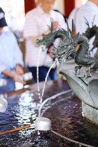 Water falling on ladle from dragon statue at fountain