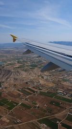 Aerial view of airplane wing over landscape against sky