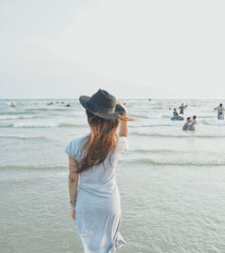 Rear view of woman standing on beach against clear sky