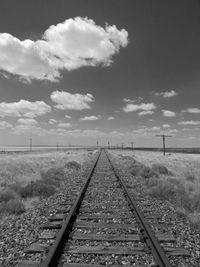 Railroad track amidst field against sky