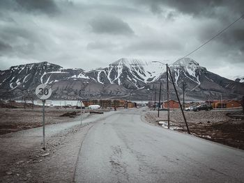 Road leading towards snowcapped mountains against sky