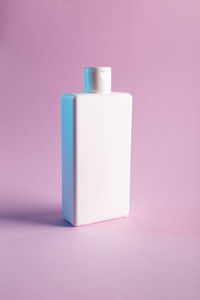 Close-up of white candle against pink background