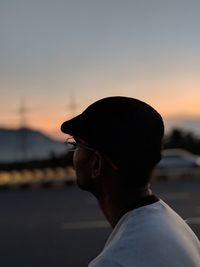 Portrait of young man looking at sea against sky during sunset