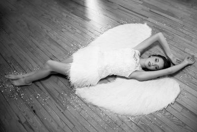 Portrait of young woman in dress lying on hardwood floor