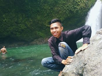 Portrait of young man on rock by lake