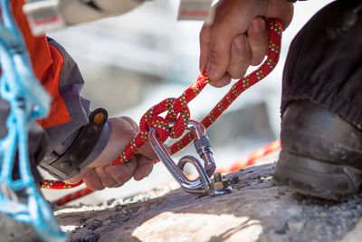 Cropped image of person tightening rope while climbing rock